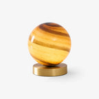This Clérachic table lamp on a plain white backdrop, a banded amber glass sphere resting on a round brass base.