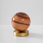 Unlit Clérachic globe lamp on a pale surface, its glass in terracotta and chocolate-brown bands above a brass disc.