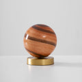 Unlit Clérachic globe lamp on a light grey backdrop, brown and rust bands wrapping the glass above a brass base.