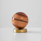 Unlit Clérachic globe lamp on a light grey backdrop, brown and rust bands wrapping the glass above a brass base.