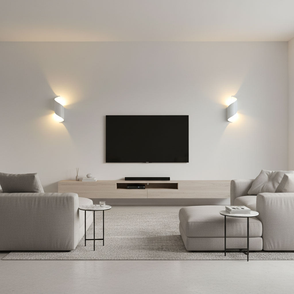Two white Clérachic wall lights either side of a wall-mounted television in a pale living room with grey sofas.