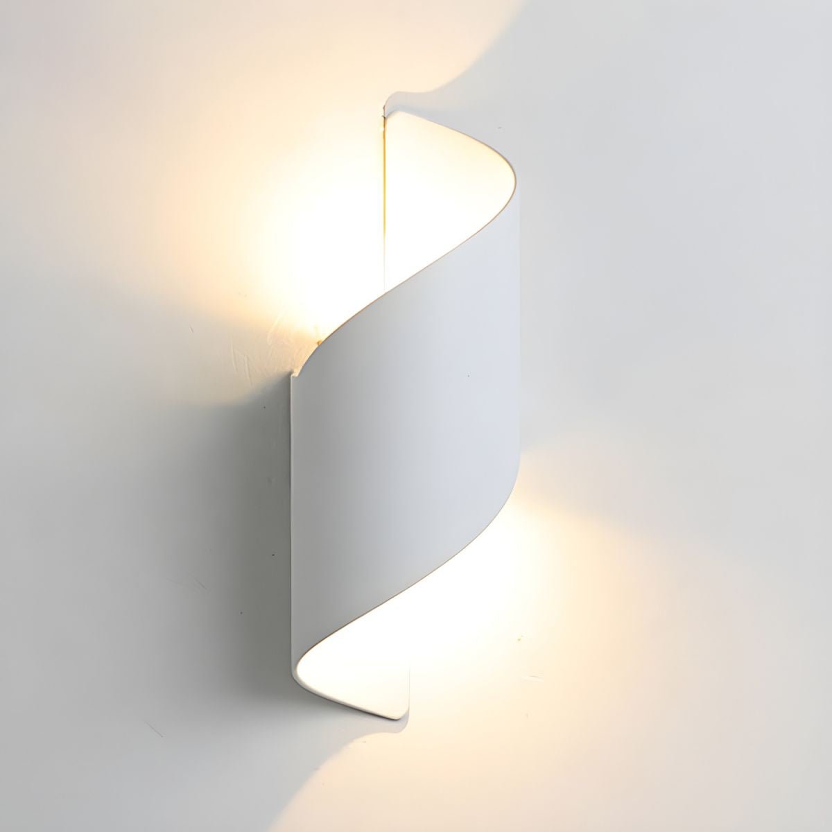 White Clérachic wall light lit against a pale wall, its twisted shell casting a soft glow above and below.
