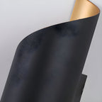 Close view of the textured black outer surface and the curled edge of this Clérachic wall light.