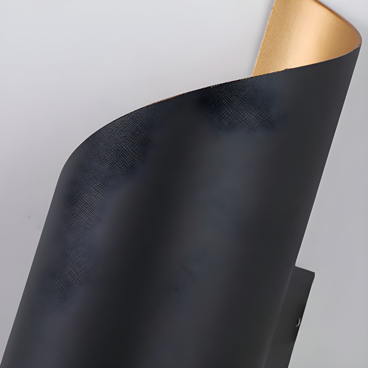 Close view of the textured black outer surface and the curled edge of this Clérachic wall light.