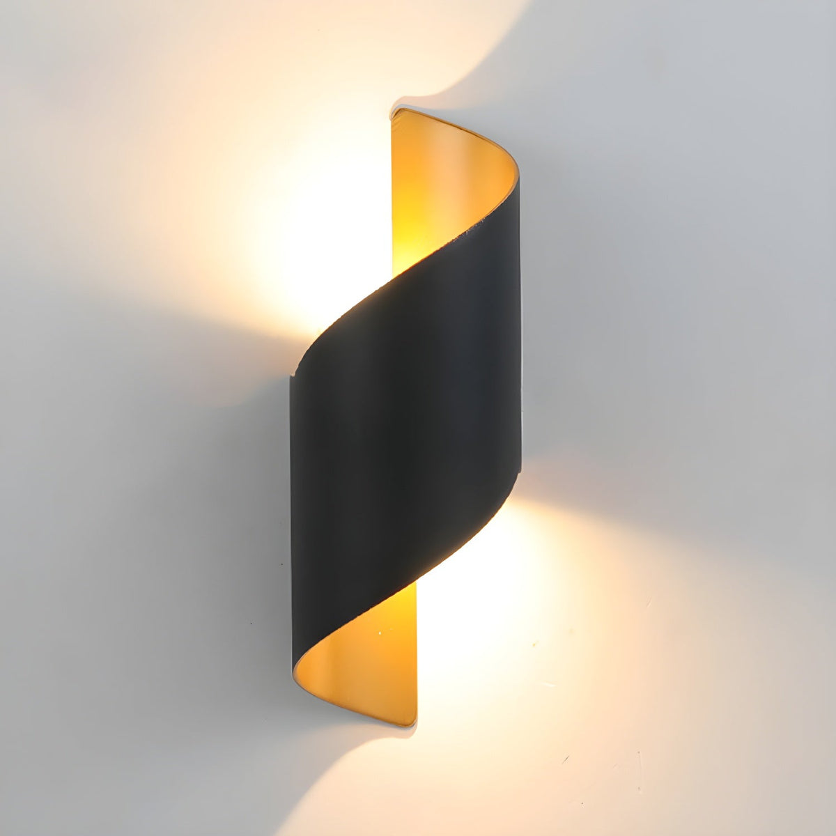 Side-on view of the black Clérachic wall light, its gold-toned inside glowing warm against a grey wall.