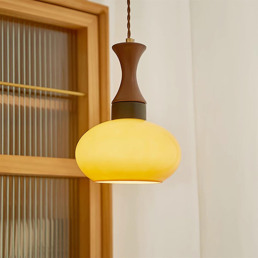 Clérachic Swirled Amber Glass Pendant Light glowing amber next to a fluted-glass cabinet door in a pale plaster corner.