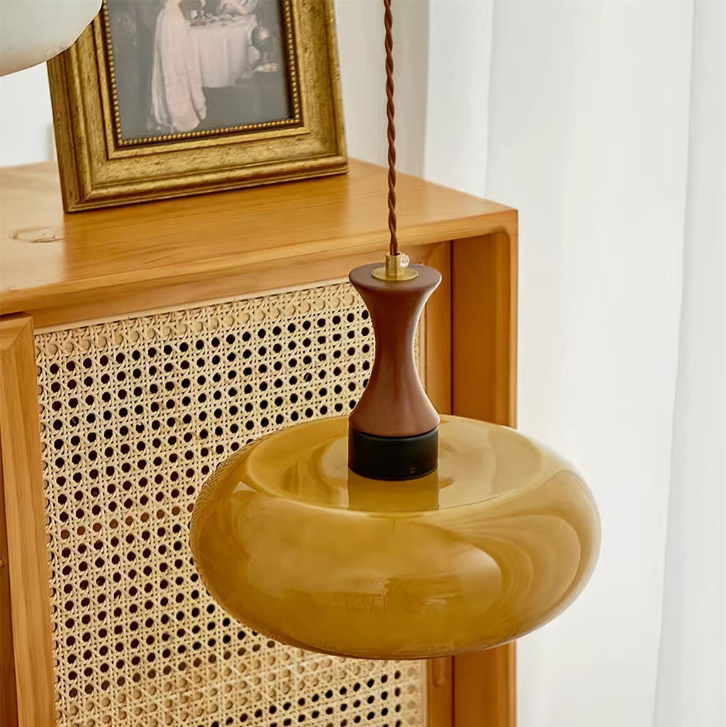 Looking down on the Clérachic Swirled Amber Glass Pendant Light, swirls visible across the wide shade above a rattan cabinet.