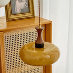 Looking down on the Clérachic Swirled Amber Glass Pendant Light, swirls visible across the wide shade above a rattan cabinet.