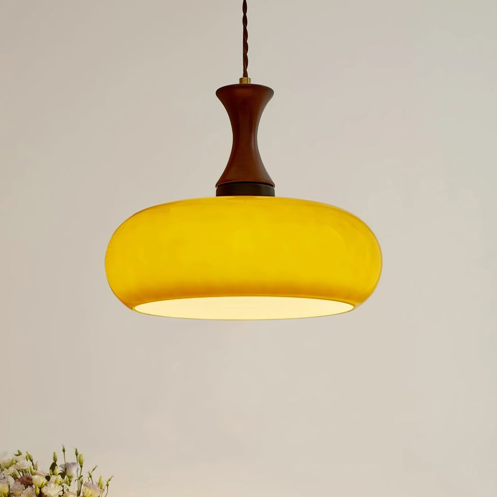 Clérachic Swirled Amber Glass Pendant Light lit to a saturated marigold, the opal diffuser visible under the wide shade rim.