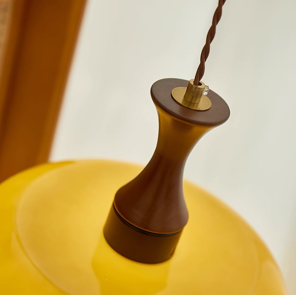 Close view of the turned walnut neck on a Clérachic amber glass pendant, with its brushed brass cord grip and set screw.