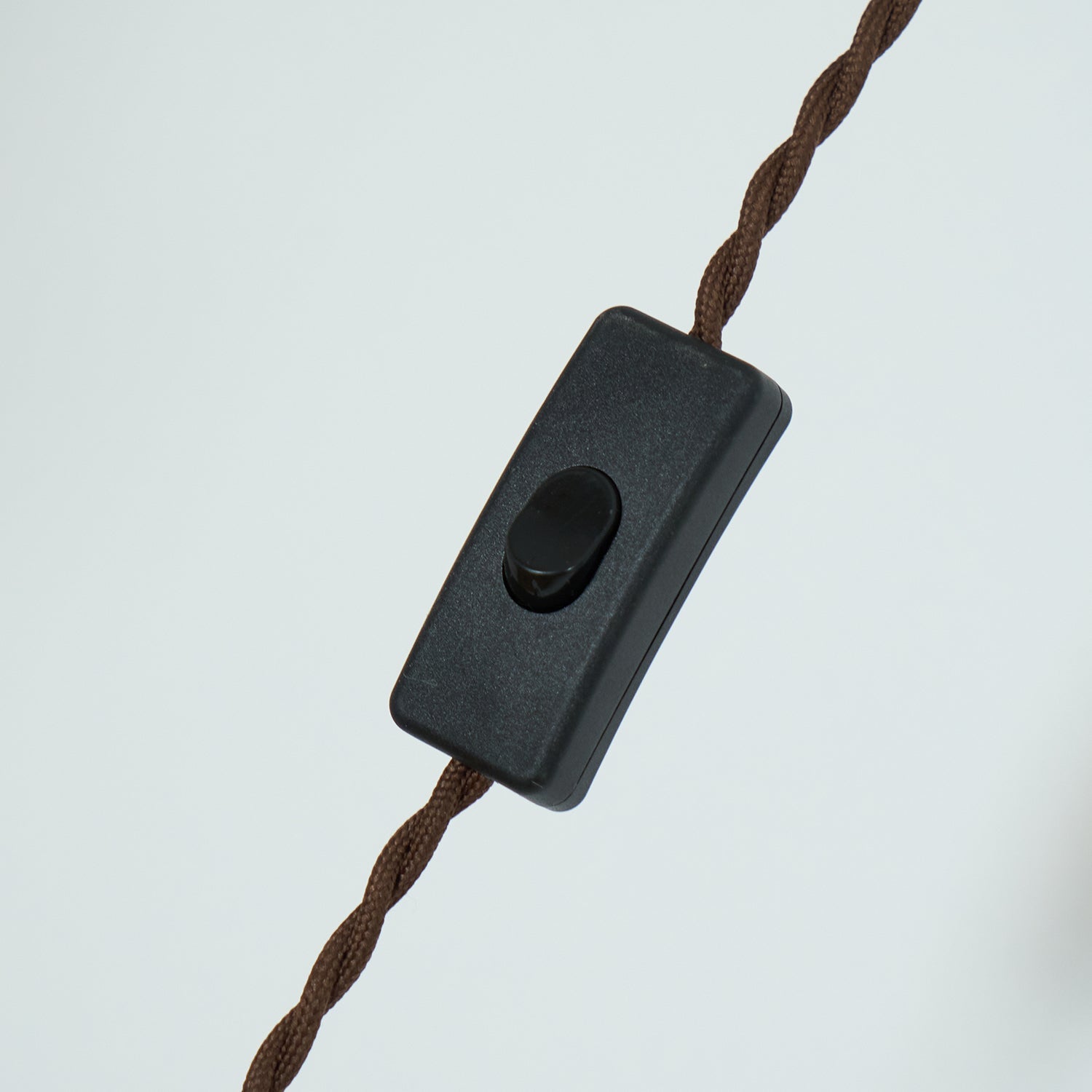 The inline black rocker switch on the twisted brown fabric cord of the Clérachic plug-in amber glass pendant light.