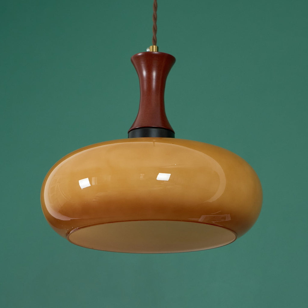 Clérachic Swirled Amber Glass Pendant Light in the wide shade against green, the opal diffuser disc visible at its base.