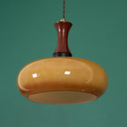 Clérachic Swirled Amber Glass Pendant Light in the wide shade against green, the opal diffuser disc visible at its base.