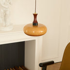 Clérachic Swirled Amber Glass Pendant Light hung beside a white mantel and panelled wall in a herringbone-floored room.