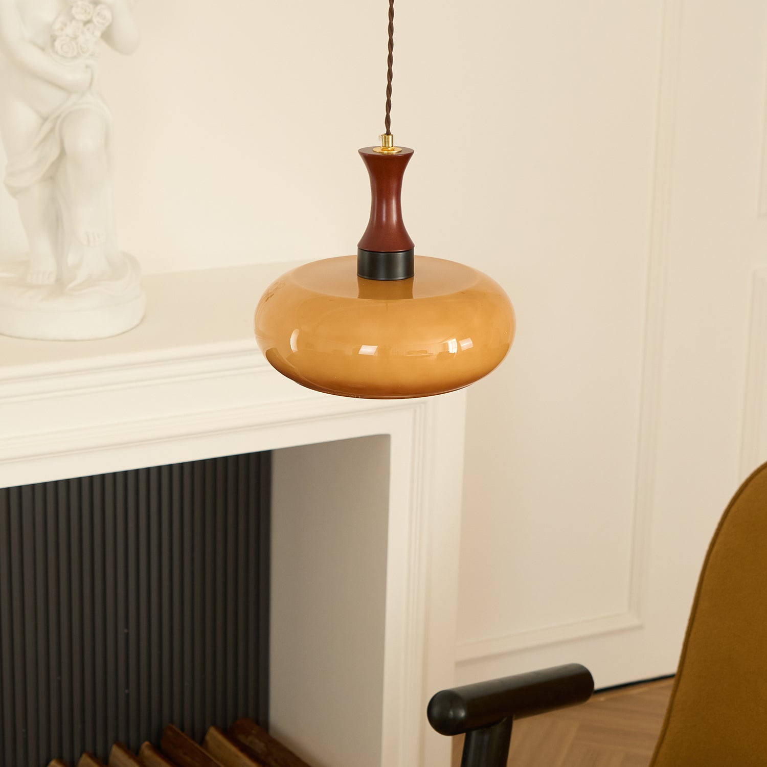 Clérachic Swirled Amber Glass Pendant Light hung beside a white mantel and panelled wall in a herringbone-floored room.