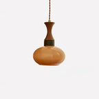 Studio shot of the small Clérachic amber glass pendant shade on its walnut neck, hanging from the twisted brown cord.