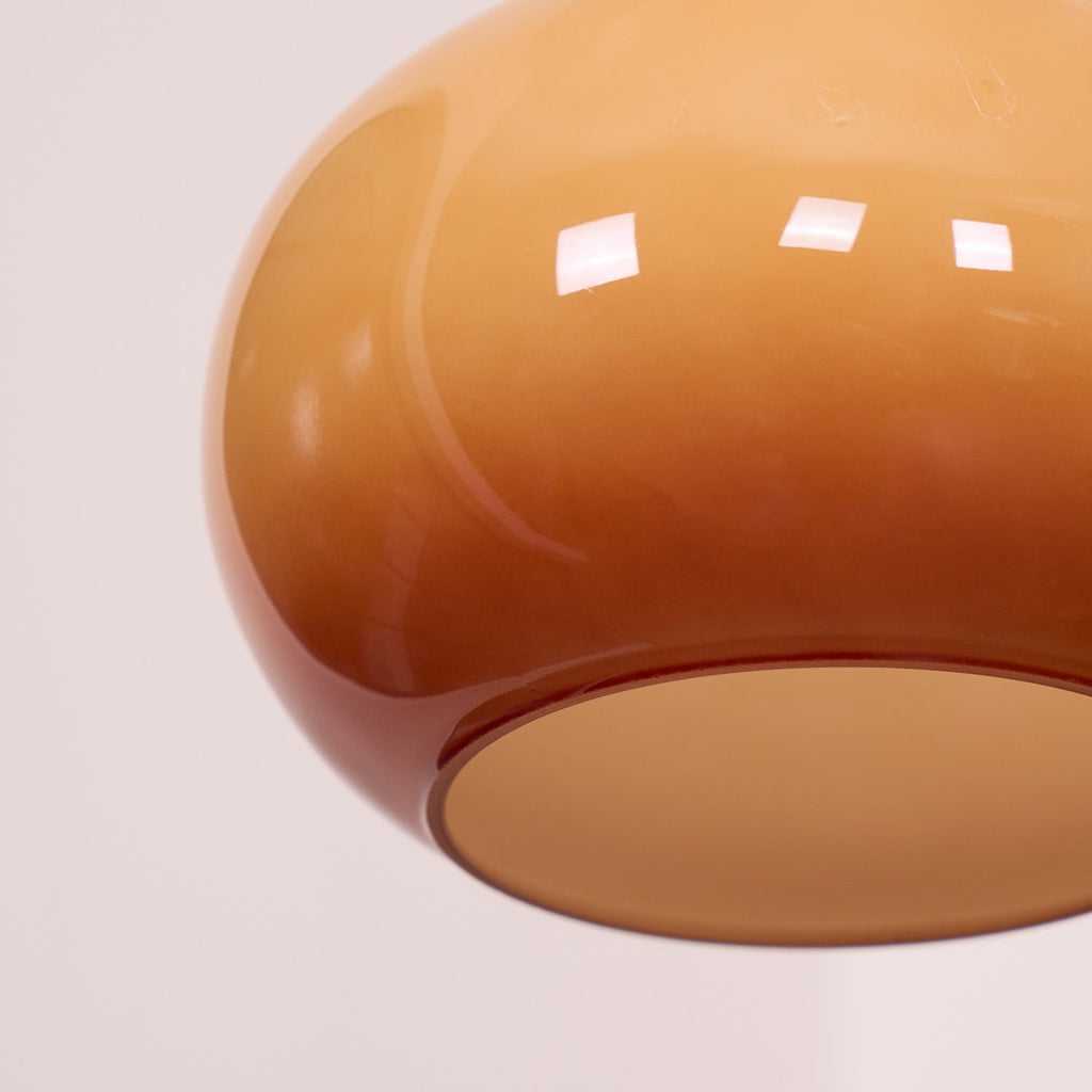 Close view of the lower curve of a Clérachic amber glass pendant shade, with the opal diffuser disc set into its mouth.