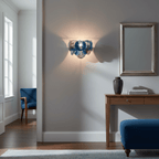 Deep blue glass-disc wall light from Clérachic casting a warm glow on a grey wall, with a mirror and a console table nearby.