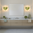 Two green glass-disc wall lights from Clérachic on either side of a frameless bathroom mirror above a floating oak vanity with a marble top.