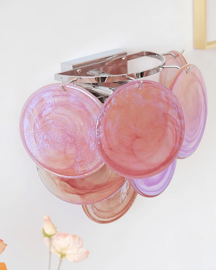 Angled close view of large pink and coral glass discs on this Clérachic wall light, with its chrome-coloured backplate at the top.