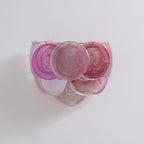 Pink and magenta glass-disc wall light from Clérachic on a pale wall, shown unlit with its discs hanging from small metal pins.