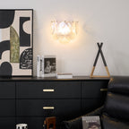 Lit iridescent glass-disc wall light from Clérachic above a black chest of drawers, with abstract art and a small ornament beside it.