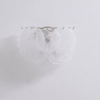 Unlit white glass-disc wall light from Clérachic with milky swirled discs on a plain pale wall, shown close up.