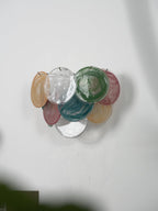 Multicolour wall light from Clérachic, unlit, with amber, clear, green, teal and rose discs, seen from a low side angle.