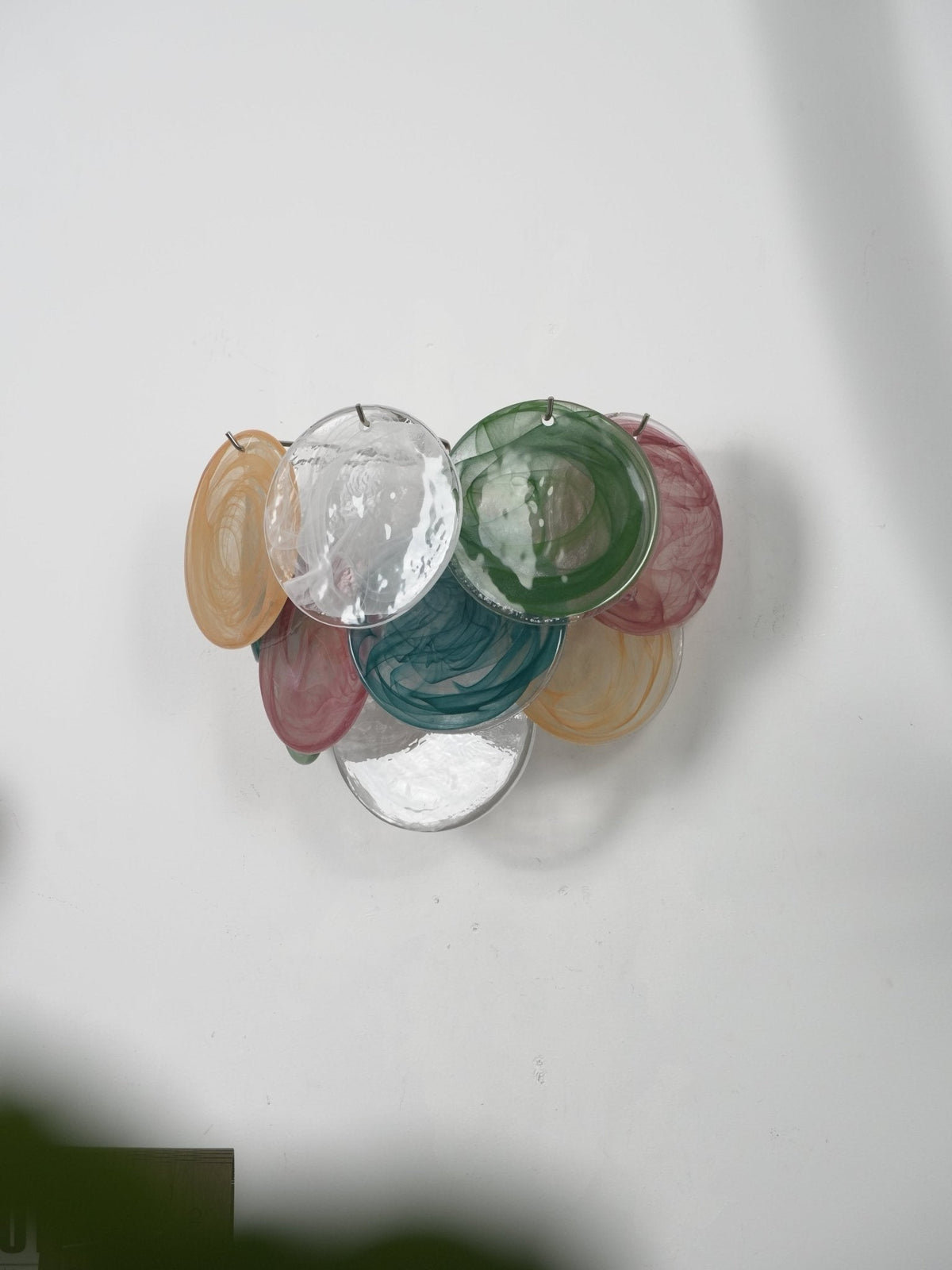 Multicolour wall light from Clérachic, unlit, with amber, clear, green, teal and rose discs, seen from a low side angle.