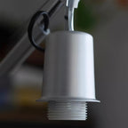 Close view of the brushed silver lamp holder with its ridged white collar, on this Clérachic swivel arm lamp.