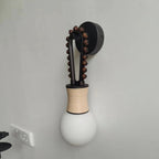 The Clérachic Sytala sconce mounted on a grey wall, showing its compact black backplate and bead arm.