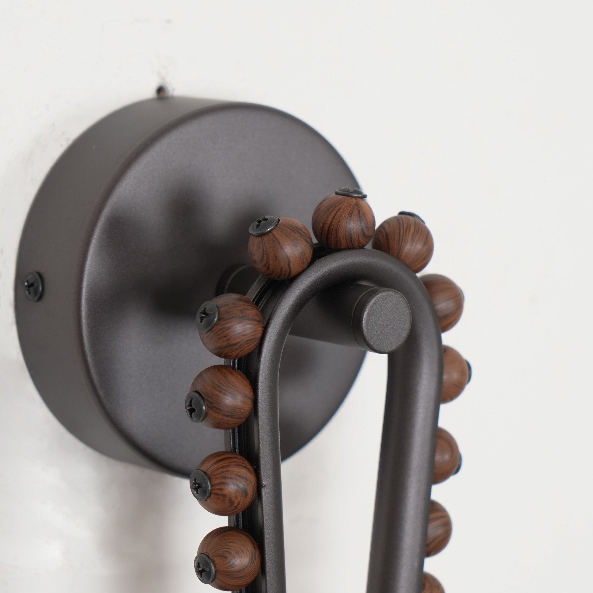 Detail of the Clérachic Sytala round black backplate, its fixing screws and walnut bead trim.