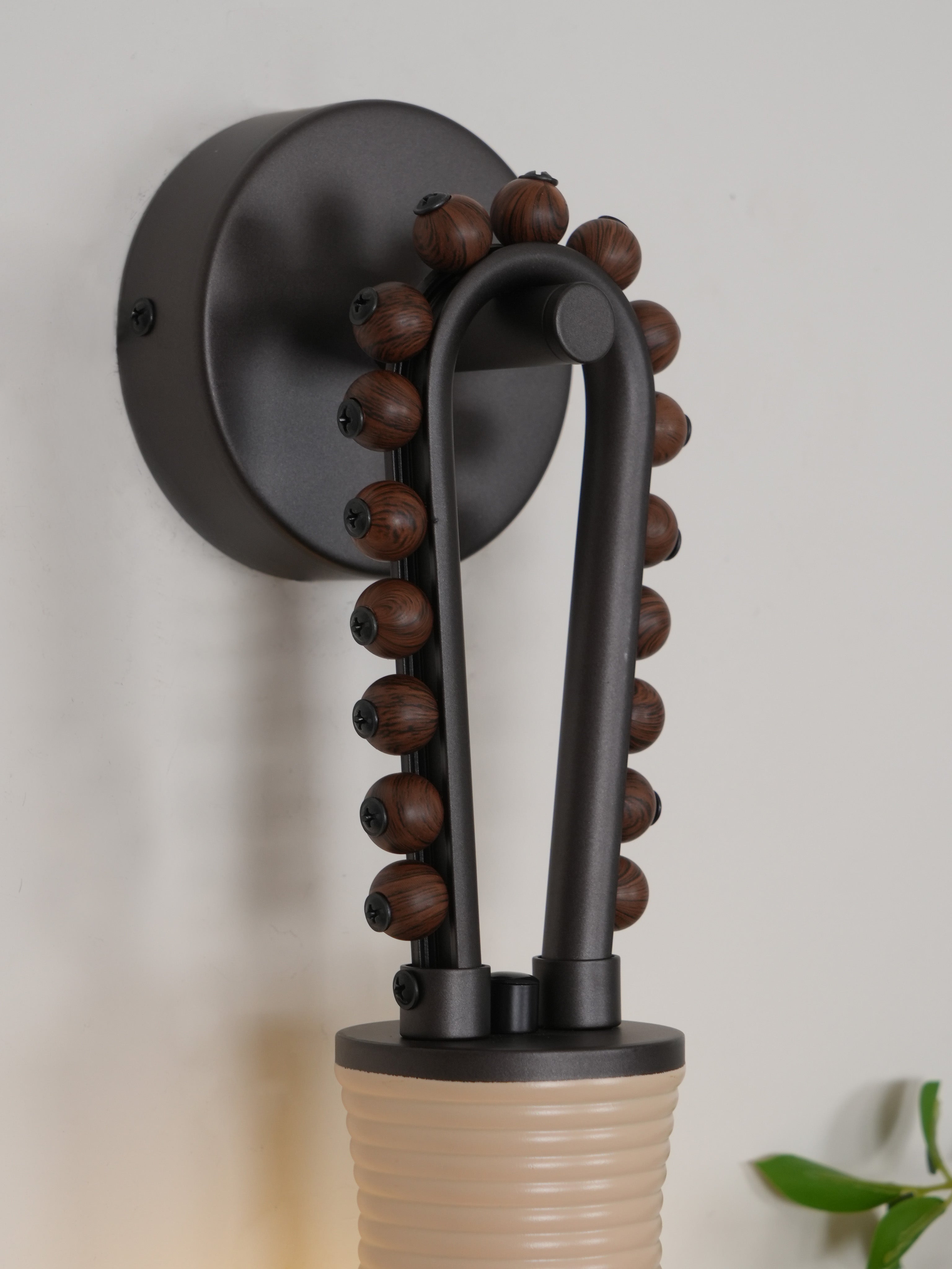 Angled view of the Clérachic Sytala sconce showing how the beaded loop bolts into the wall plate.