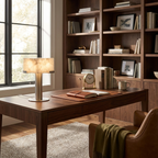 This Clérachic table lamp lights a walnut desk in front of a bookshelf lined with framed photos and books.