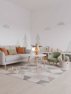 Distant view of a Clérachic squirrel lamp on a coffee table in a pale living room with a grey sofa and a geometric rug.