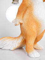 Close view of the squirrel's paws and body below the round bulb on this Clérachic lamp, the orange fur finely textured.