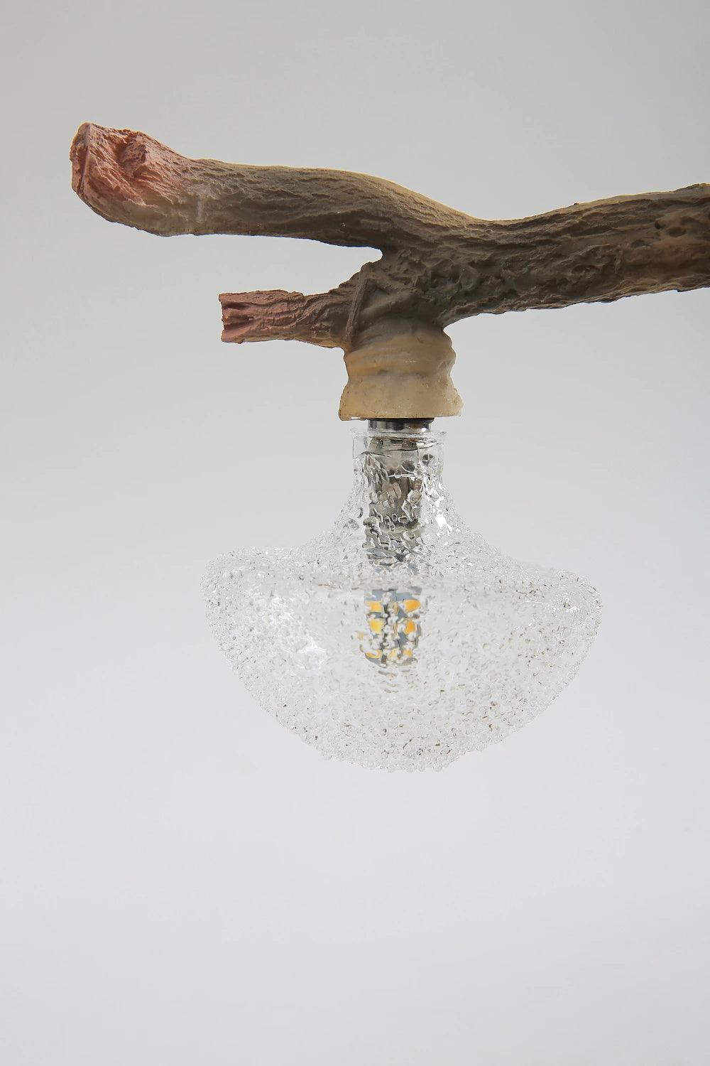 Close view of the carved branch, the bulb socket and the ribbed clear glass bulb on this Clérachic squirrel lamp.