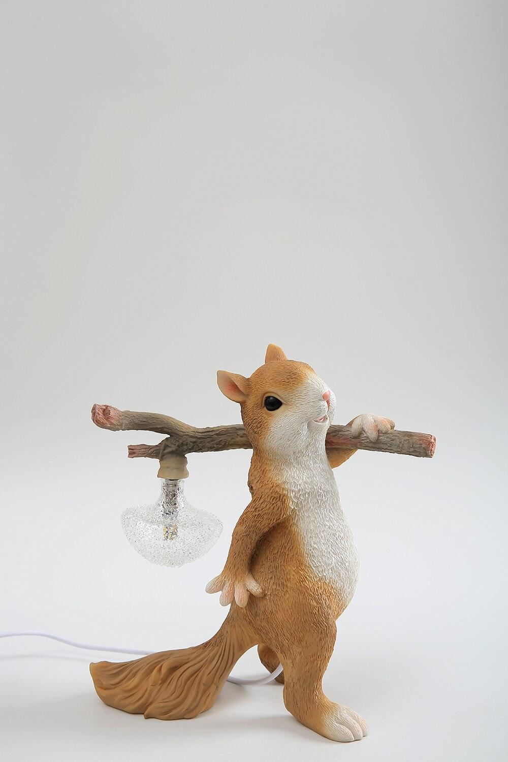 Side view of the Clérachic squirrel lamp on a grey backdrop, with its ribbed glass bulb hanging from the branch.