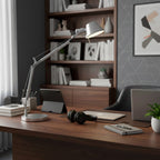 Clérachic desk lamp on a walnut desk with a laptop, a tablet and a pair of headphones, in front of a bookcase.