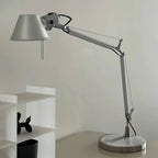 Close view of the conical shade, jointed arm and ridged base of this Clérachic desk lamp, with a small shelf nearby.