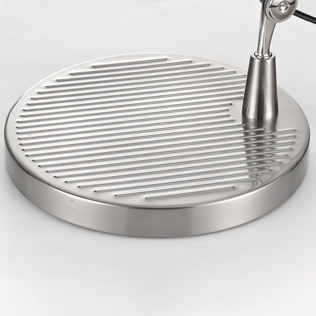 Close view of the round chrome base of this Clérachic desk lamp, with its ridged top and a slim central stem.