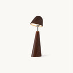 Walnut-finish Clérachic table lamp with a tilted dome shade on a slim metal stem and a tapered wood-grain base, lit on a plain backdrop.