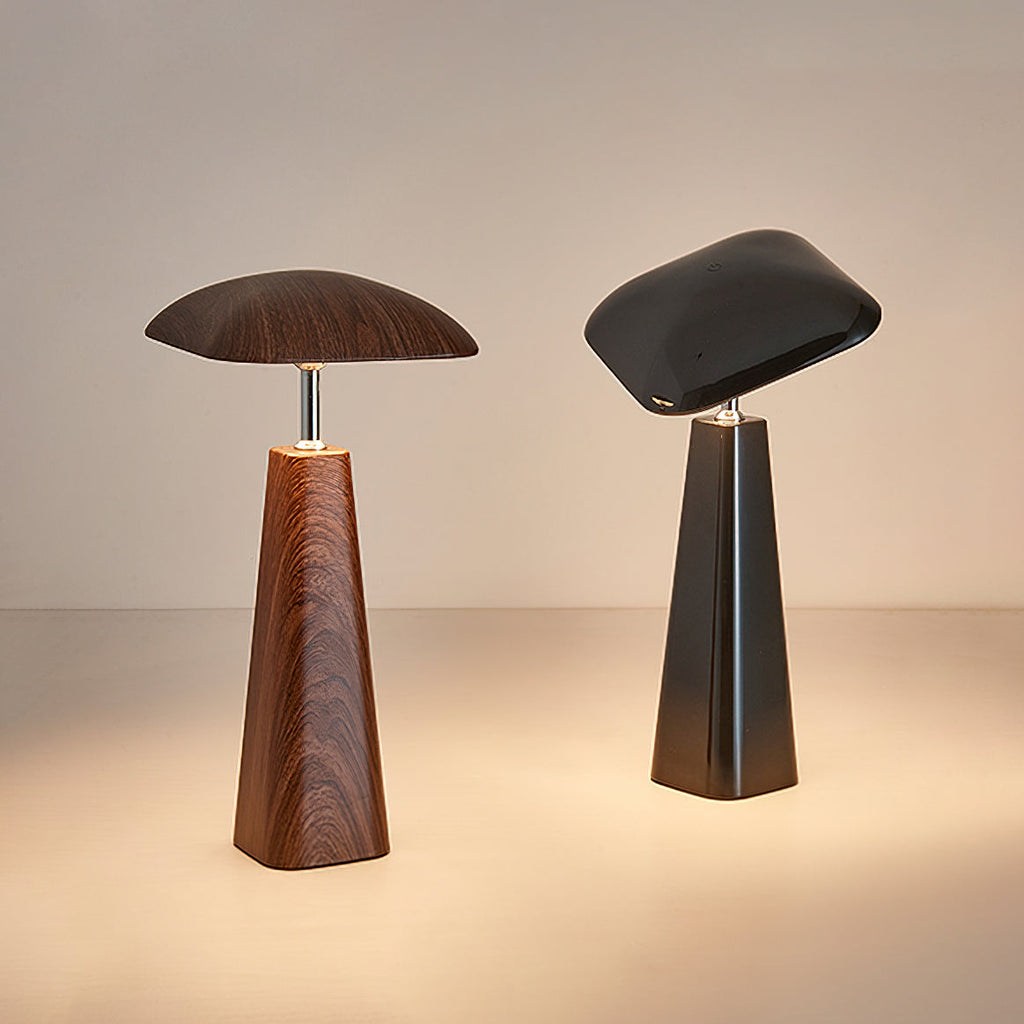A walnut and a black Clérachic table lamp side by side, their wide shades tilted and warm light pooling on the surface below.
