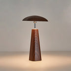 Walnut Clérachic table lamp with a wide, low shade over a tall tapered wood-grain base, warm light spreading across the surface.