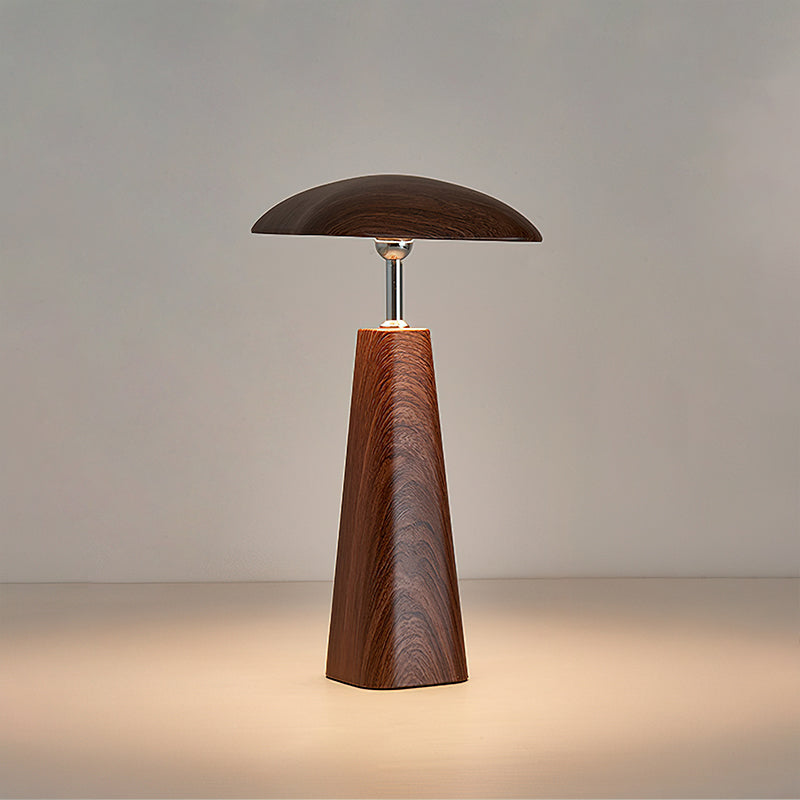 Walnut Clérachic table lamp with a wide, low shade over a tall tapered wood-grain base, warm light spreading across the surface.