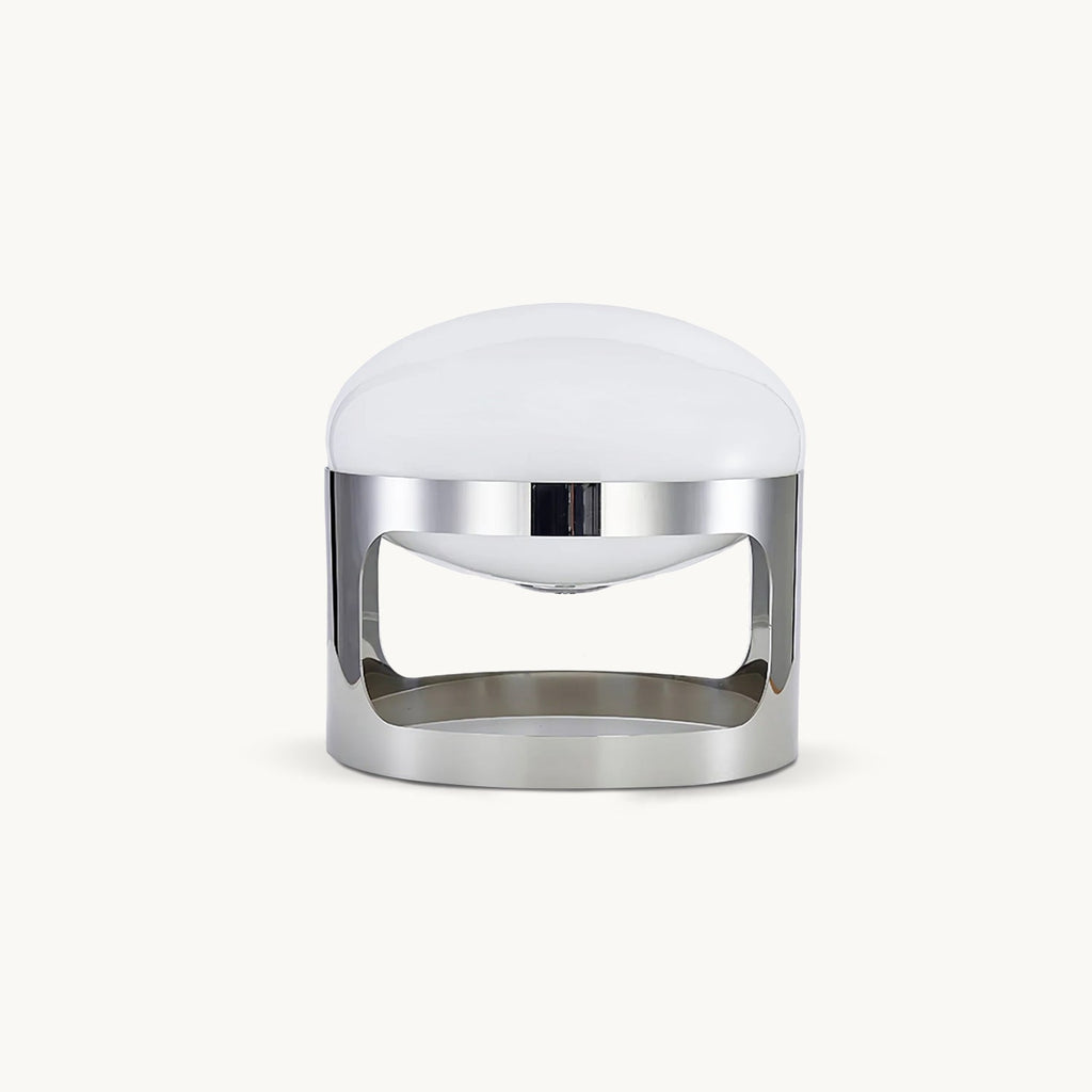 A Clérachic table lamp with a domed opal white shade and a polished chrome band with curved cutouts, on a plain white backdrop.