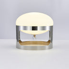 Front view of the Clérachic table lamp on a pale grey surface, showing the opal dome, the chrome band and the open lower section.