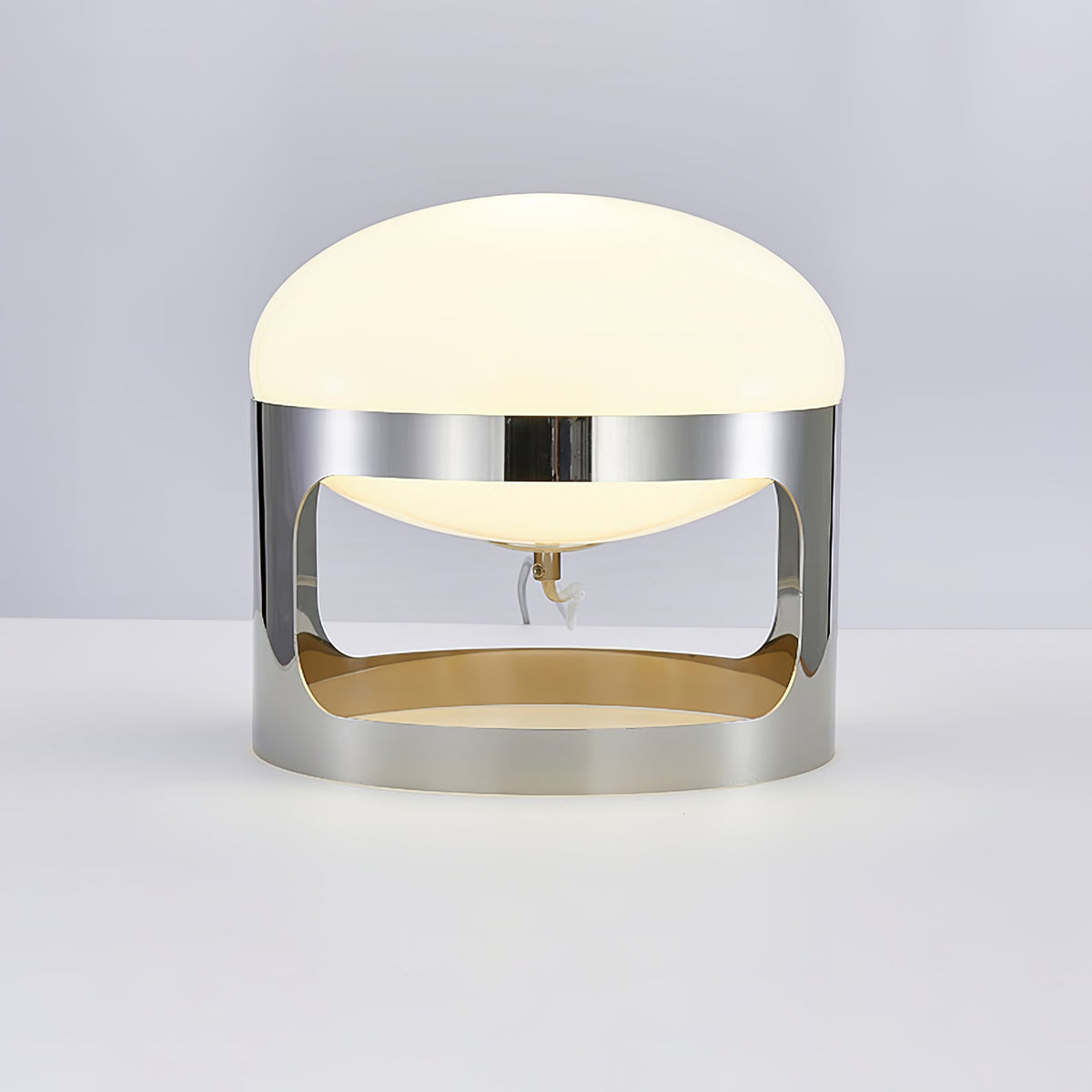 Front view of the Clérachic table lamp on a pale grey surface, showing the opal dome, the chrome band and the open lower section.