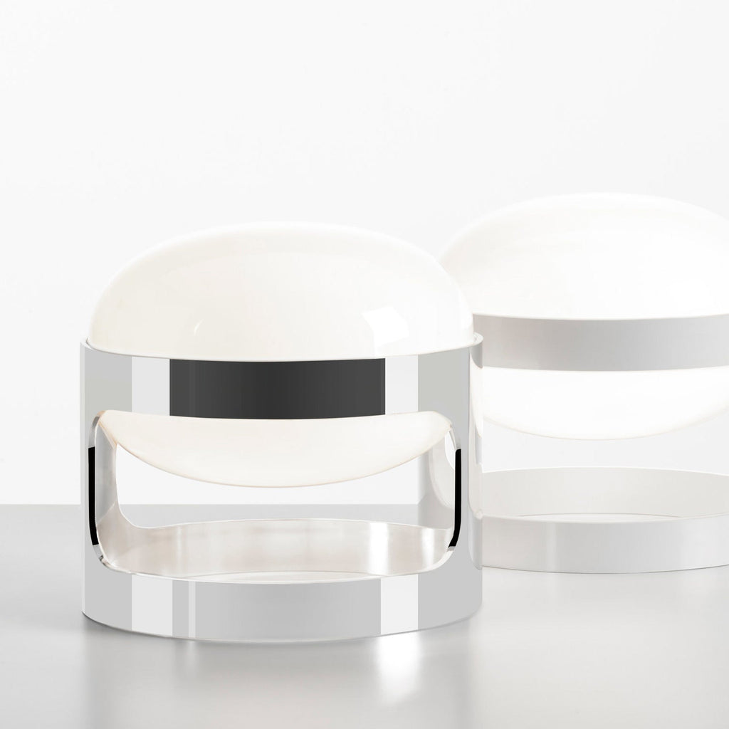 A chrome Clérachic table lamp in the foreground, with a white-finish version of the same shape softly blurred behind it.