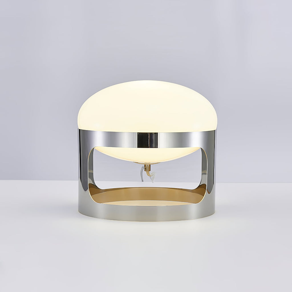 This Clérachic table lamp lit on a pale grey backdrop, its dome glowing soft white above the chrome band.